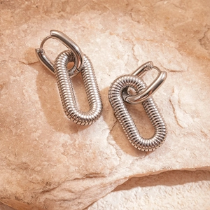 Silver paperclip earrings with ribbed texture and 18k gold plating on stone background