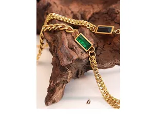 Macro detail of gold chunky cuban chain set with emerald green and black rectangle stones
