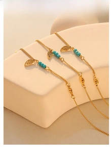 Detailed shot of gold titanium anklet with turquoise beads and hollow leaf charms
