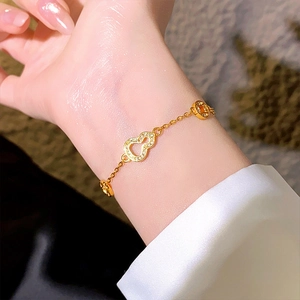Gros plan sur le bracelet doré avec pendentif gourde, pièce et oxydes de zirconium