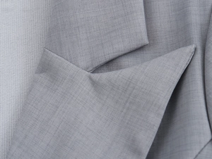 Gros plan du revers cranté et de la texture sergé d'une veste de tailleur grise