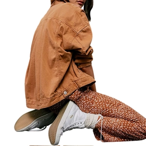 Fashionable tan denim jacket paired with floral trousers and white high-top canvas shoes