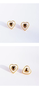 Detail of white enamel heart earrings with gold metal frame and dotted texture