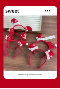 Collection of festive red plush Christmas headbands with stars and hats on a wooden desk
