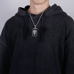 Detail of a vintage silver lion head shield pendant necklace on a black hoodie