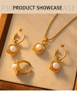 Detail view of gold titanium jewelry set with square hammered texture and white pearls