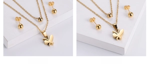 Close-up of golden butterfly pendant necklace and ball stud earrings jewelry set