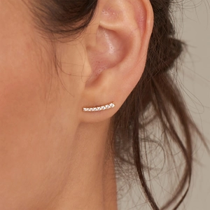 Close-up of golden curved ear crawler earrings with minimalist shimmering zircons