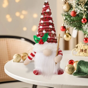 Charming glowing Christmas gnome with knitted hat standing near a festive tree