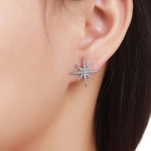 Close-up of elegant silver star earrings with pavé zircons worn on ear for daily style