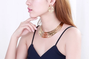 Detailed view of model wearing gold star-patterned choker and earring set jewelry