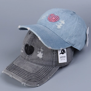 Close-up of distressed denim baseball caps with CUPID embroidery and ripped details