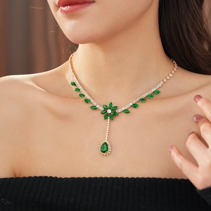 Detail of elegant gold necklace with green zircon flower and teardrop pendants on model