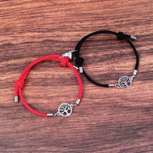 Detail of red and black magnetic couple bracelets with Tree of Life charms on wood