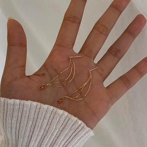 Macro shot of gold tassel chain earrings held by hand to show size and scale