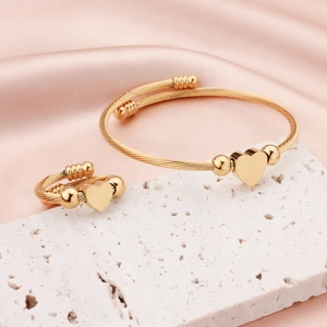 Golden heart charm stainless steel cable wire bracelet and ring jewelry set on a stone stand