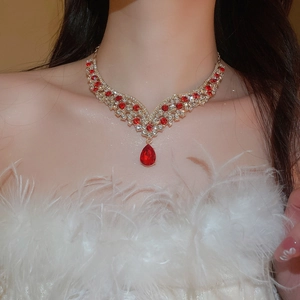 Detailed close-up of a vintage V-shaped necklace with red teardrop crystal pendants