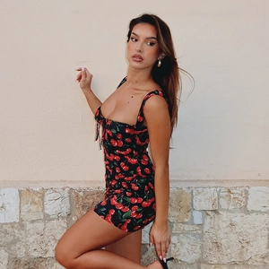Close-up of slim-fit cherry print mini dress with thin straps and bow detail