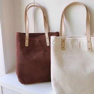 Solid corduroy tote bags in brown and white with leather handles on white background