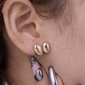 Detailed close-up of polished gold geometric waterdrop earrings worn on earlobe