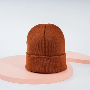 Détail du bonnet en maille côtelée orange montrant le tissage texturé sur un support