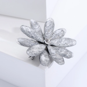 Detail of silver flower brooch with textured petals and a sparkling crystal center