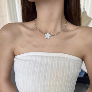 Detailed close-up of a silver chain necklace with a white enamel flower pendant on a neck