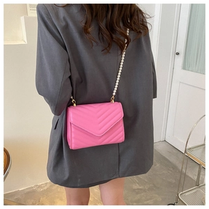 Detail of pink chevron quilted crossbody bag featuring a white pearl bead strap