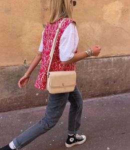 Detail of pink floral double-sided vest layered with white T-shirt and grey jeans
