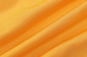 Vue macro de la texture du tissu orange avec des détails de tissage en sergé