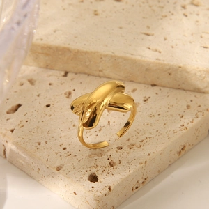 Nahaufnahme des goldenen Seesternknoten-Rings mit X-Design auf Natursteinsockel