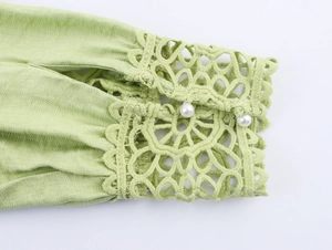 Detail of light green lantern sleeve with lace hollow-out embroidery and pearl buttons