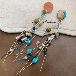 Detail of bohemian earrings featuring turquoise, wooden beads, and long woven tassels