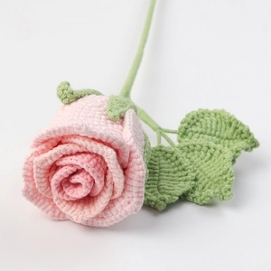 Detailed view of hand-knitted pink yarn rose with green stem and leaves decor