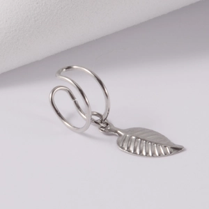 Detail of silver stainless steel double ear cuff with leaf pendant on a light background