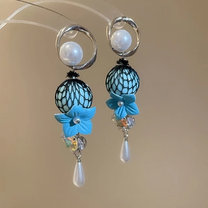 Detailed view of floral drop earrings with blue petals and white teardrop pearls