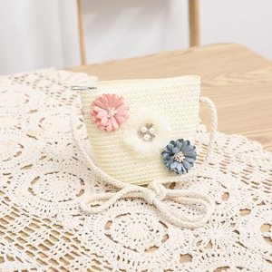 Dettaglio della borsa a tracolla in paglia per bambini con tre fiori decorativi in rilievo