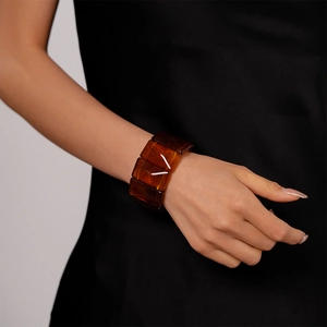 Macro shot of amber-colored rectangular acrylic link bracelet on a woman's wrist