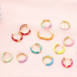 Close-up of colorful enamel huggie hoop earrings in various vibrant shades and patterns
