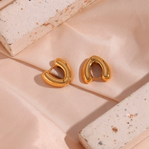 Detailed close-up of 18K gold plated chunky heart earrings on pink silk background
