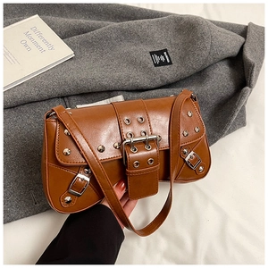 Close-up of brown punk shoulder bag featuring silver metal rivets and leather buckle straps
