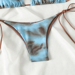 Close-up of sky blue and brown tie-dye bikini bottoms with side string ties on white fabric