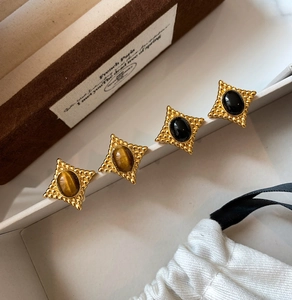 Détail des boucles d'oreilles rétro en forme d'étoile avec œil de tigre et gemmes