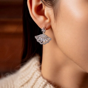 Close-up of sparkling fan-shaped zircon earrings worn by a model in warm lighting