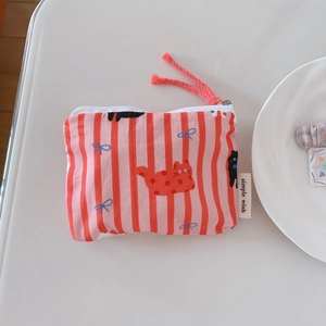 Detail of fabric cat coin purse with pink stripes and simple wish label on white desk
