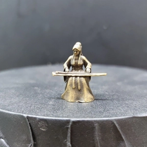 Detailed macro view of a vintage brass figurine depicting a woman playing the guqin zither