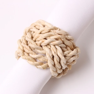 Close-up of a woven natural corn husk napkin ring on white fabric with detailed texture