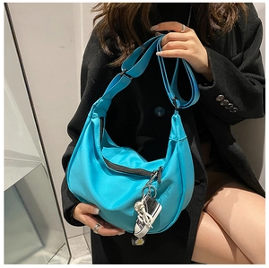 Close-up of blue nylon crescent bag featuring sneaker charm and daisy strap detail