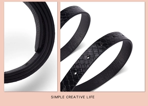 Detail of slim black faux snakeskin leather belt with textured scales and round holes