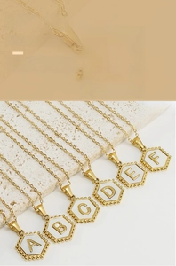 Detail of 18K gold plated hexagonal shell initial necklace with A-Z alphabet charms